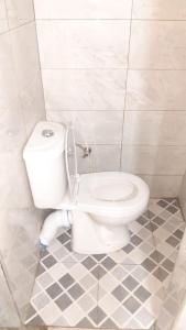 a white toilet in a bathroom with a tiled floor at Lala Elyacout in Azzaba