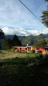 a house in a field with mountains in the background at La Estancia de Runtún Km 7 in Baños