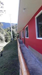 a red building with a fence next to it at La Estancia de Runtún Km 7 in Baños