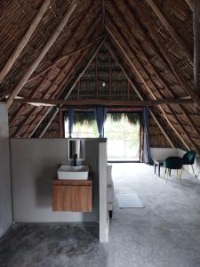 Habitación en un edificio con techo de paja, lavabo y sillas. en Casa Mate BeachFront Cabañas El Cuyo, en El Cuyo