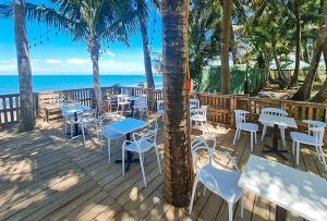una terraza con mesas y sillas y el océano en RedDoorz @ Balai Baibai Cagayan, en Bawa