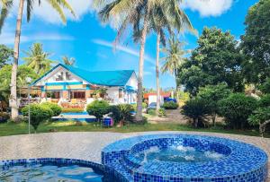 a pool in front of a house with palm trees at RedDoorz @ Balai Baibai Cagayan in Bawa