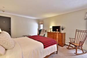 1 dormitorio con 1 cama, vestidor y TV en The Birch Ridge- Colonial Maple Room #1 - Queen Suite in Renovated Killington Lodge home en Killington