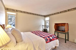 um quarto com uma cama, uma televisão e janelas em One-Bedroom House em Killington