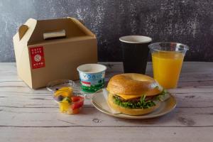 a sandwich on a plate next to a box and orange juice at HOTEL R9 Kujukuri "ex Casual Resort COFF Ichinomiya" in Ichinomiya