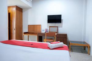 a bedroom with a bed and a desk and a tv at Capital O 93602 Hotel Tempoa Inn in Jambi