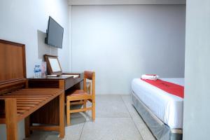 a bedroom with a bed and a desk with a television at Capital O 93602 Hotel Tempoa Inn in Jambi