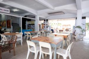 a restaurant with wooden tables and white chairs at Capital O 93602 Hotel Tempoa Inn in Jambi