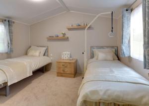 a bedroom with two beds and a dresser in it at Merryfield And Sandfield in Chapel Saint Leonards