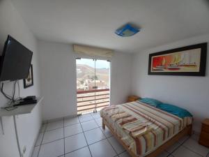 una camera con un letto e una televisione di DÚPLEX CON VISTA A TODA LA BAHÍA DE NAPLO a Pucusana