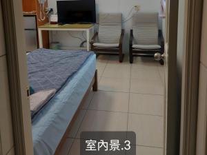 een kamer met een bed, 2 stoelen en een bureau bij 南田旅宿 in Nan-k'eng