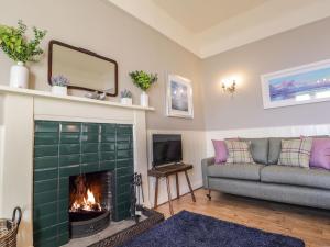 sala de estar con chimenea y sofá en Ferry Cottage - Balmacara en Coillemore