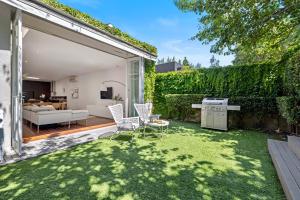 een achtertuin met een gazon met een tafel en stoelen bij St Kilda Style - Stunning 3 Bedroom House in Melbourne