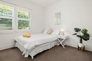 a white bedroom with a bed and a desk and windows at St Kilda Style - Stunning 3 Bedroom House in Melbourne +66 photos