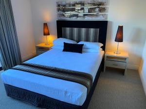 1 dormitorio con 1 cama grande con sábanas y almohadas azules en Parklane Apartments en Fremantle