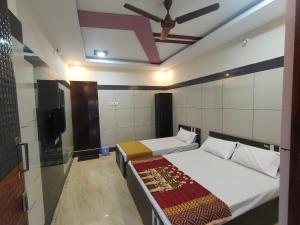 a bedroom with two beds and a ceiling fan at Sar Raj S R RESIDENCY in Vellore