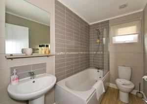 a bathroom with a sink and a tub and a toilet at Jamies Cragg Holiday Park in Welburn