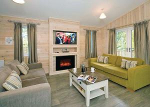 a living room with a couch and a fireplace at Jamies Cragg Holiday Park in Welburn