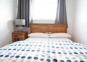 a bed with a blue and white comforter and a window at North Shore Holiday Park in Winthorpe