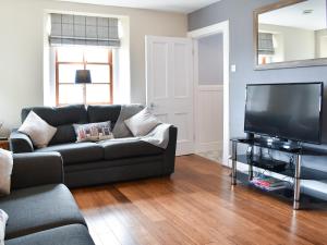 a living room with a couch and a flat screen tv at Acarsaid Cottage in Portknockie