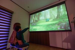 a child is pointing at a projection screen of a forest at Katsuren Seatopia 勝連シートピア in Uruma