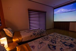 two beds in a room with a projection screen at Katsuren Seatopia 勝連シートピア in Uruma