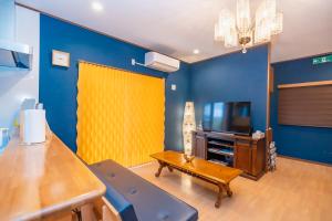 una sala de estar con paredes azules y una pantalla amarilla en Katsuren Seatopia 勝連シートピア en Uruma