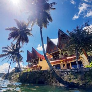 una casa en una isla rocosa en el agua con palmeras en Mas Cottages en Tuk Tuk