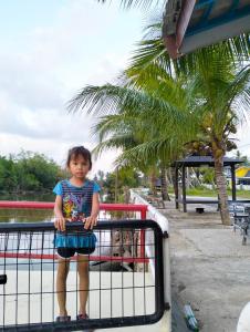 a little girl standing on top of a fence at Airport Kota Bharu Transit Inn in Kota Bharu