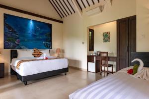 a bedroom with two beds and a desk at Alamanda Lovina Resort in Lovina
