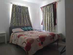 a bedroom with a bed with a floral comforter and two windows at Flia Alcantara CG in Naiboa