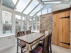 a conservatory dining room with a wooden table and chairs at Badger Cottage in Cressbrook