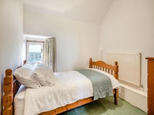 um quarto com uma cama com lençóis brancos e uma janela em Badger Cottage em Cressbrook