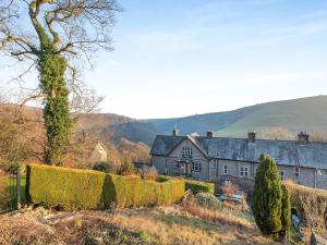 an old house on a hill with hedges in front of it at Badger Cottage in Cressbrook