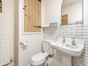 a white bathroom with a toilet and a sink at Badger Cottage in Cressbrook
