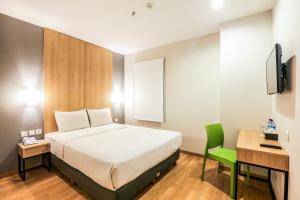 a bedroom with a bed and a desk and a television at Hotel Citradream Bandung in Bandung