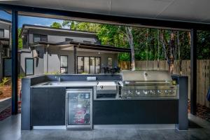 uma cozinha exterior com um lavatório e comodidades para churrascos em Tropicana Villas at Clifton Beach em Clifton Beach
