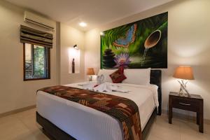 a bedroom with a bed with a painting on the wall at Alamanda Lovina Resort in Lovina