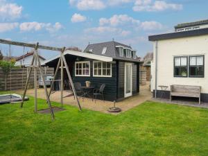 a backyard with a swing set and a house at Quaint Summer Holiday Home in Egmond Binnen in Egmond-Binnen