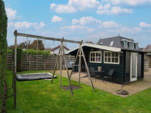 una pequeña casa con un columpio en el patio en Quaint Summer Holiday Home in Egmond Binnen, en Egmond-Binnen