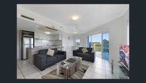 a living room with two couches and a kitchen at Koola Beach Apartments Bargara in Bargara