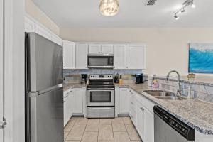 a kitchen with white cabinets and a stainless steel refrigerator at Blue Oasis Beach Vacation Home with Private Pool & Hot Tub in Panama City Beach