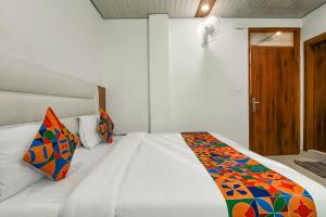 a bedroom with a white bed with a colorful blanket on it at FabExpress Sagar Residency in Mussoorie