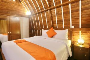 1 dormitorio con 1 cama blanca grande con manta naranja en 37 Sunset Village Bali, en Canggu