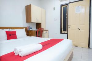 a bedroom with a white bed with towels on it at RedDoorz near Tugu Pers Jambi in Jambi