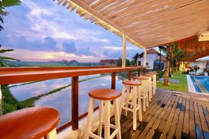 a bar with stools on a deck next to a pool at 37 Sunset Village Bali in Canggu