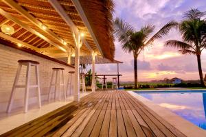 a house with a wooden deck and a swimming pool at 37 Sunset Village Bali in Canggu