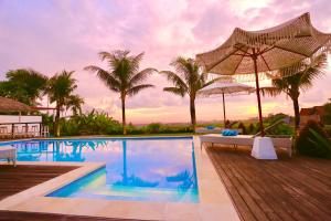 a swimming pool with an umbrella and palm trees at 37 Sunset Village Bali in Canggu +46 photos