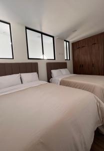 2 Betten in einem Zimmer mit 2 Fenstern in der Unterkunft Departamento nuevo en el corazón de la Condesa in Mexiko-Stadt