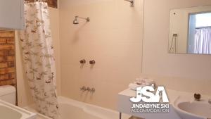 a bathroom with a tub shower and a sink at Ellswood 1 in Jindabyne